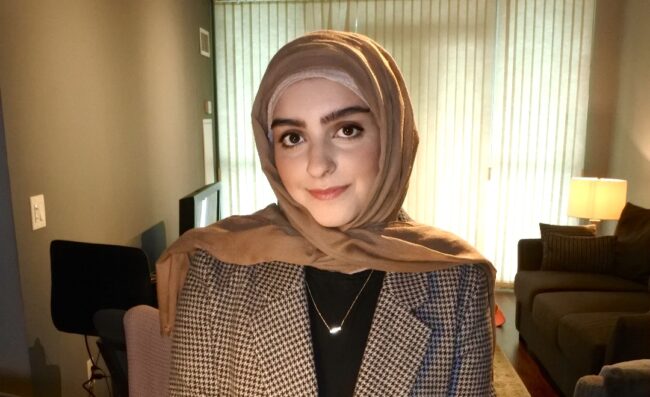 Woman in a beige hijab and a patterned blazer.