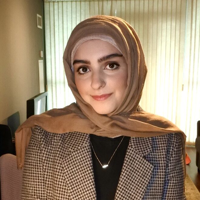 Woman in a beige hijab and a patterned blazer.