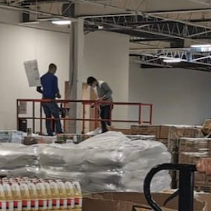 Two men standing in a warehouse.