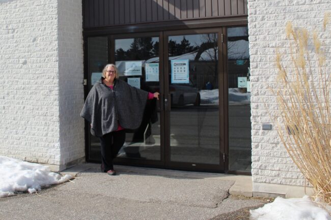 Lori Pilatzke holds the handle of St. David Anglican-Lutheran Church's glass front doors on a Sunny afternoon.