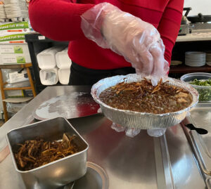 A staff member adding crispy onion to the cooked lentils.