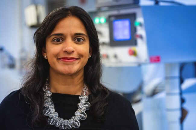 Women wearing a glass orb necklace smiling.