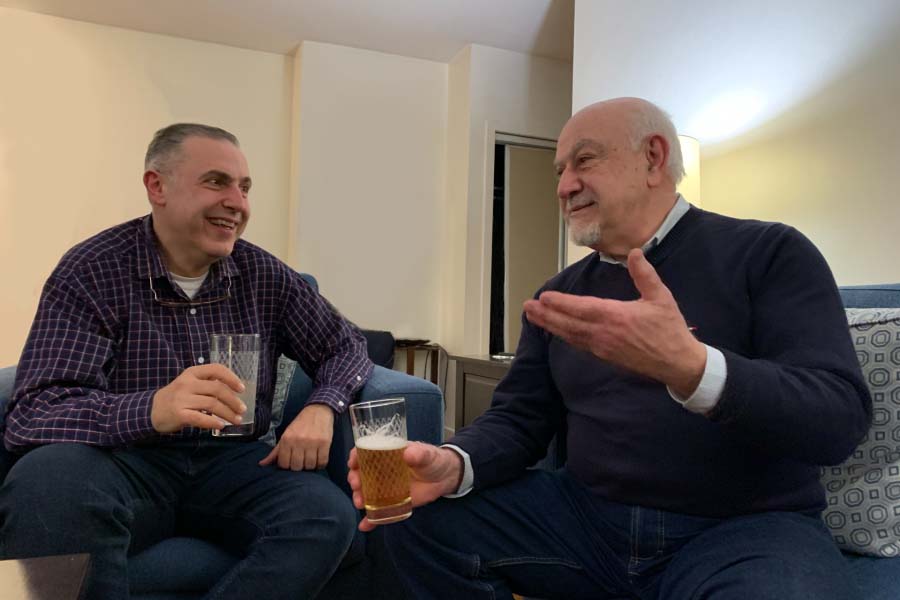 Two men having a conversation, holding drinks.