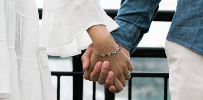 Couple holding hands, evil eye bracelet.