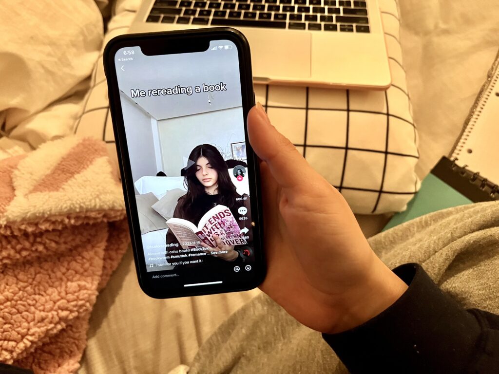 A phone showing a TikTok of a girl reading a book