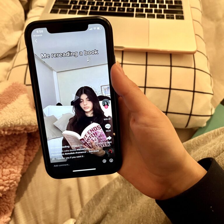 A phone showing a TikTok of a girl reading a book