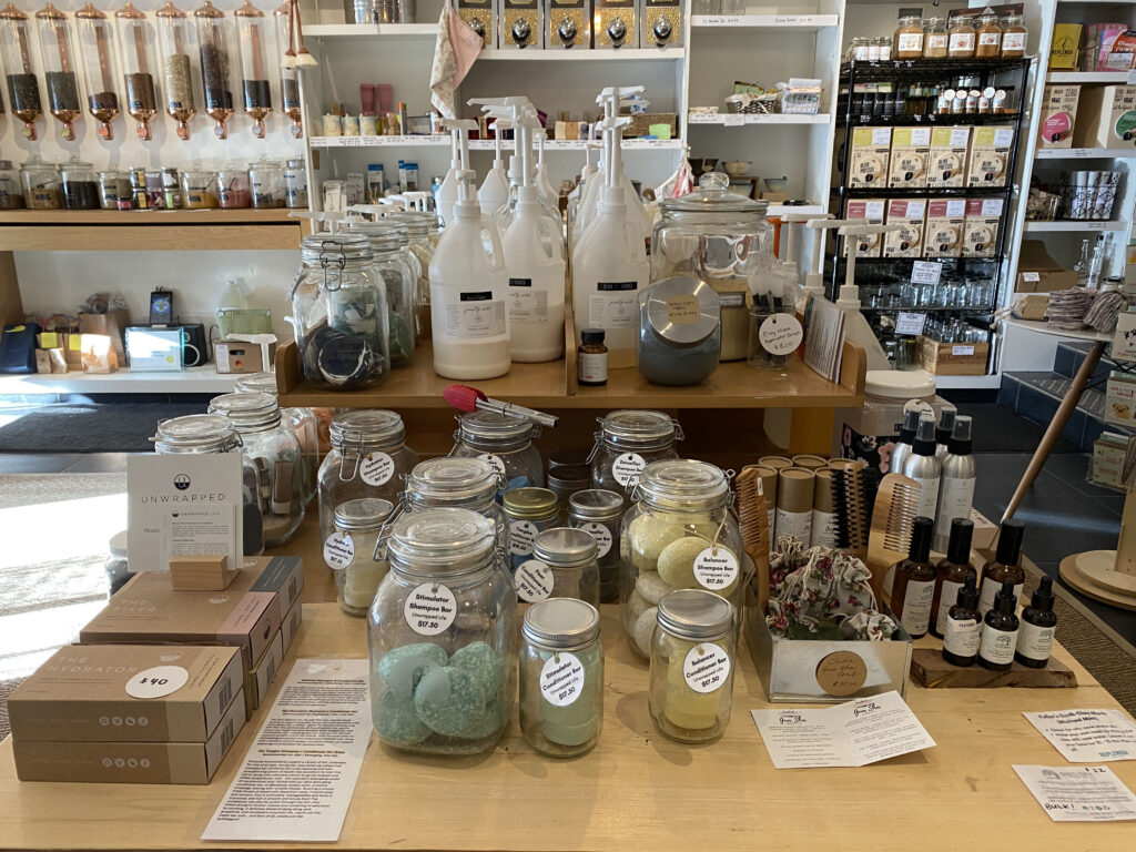 Various products like shampoo bars and large jars containing products to be put in smaller containers sit on a table in the middle of the store.