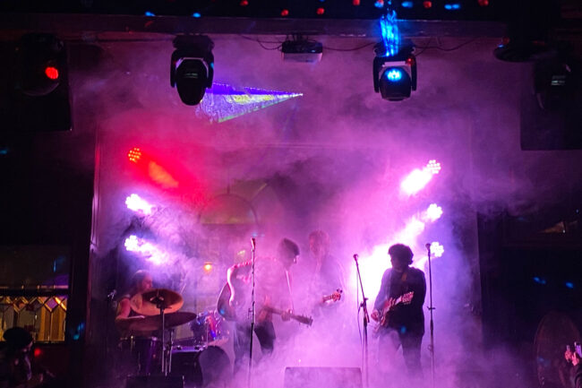 Musicians performing on a colourful, smoke-filled stage