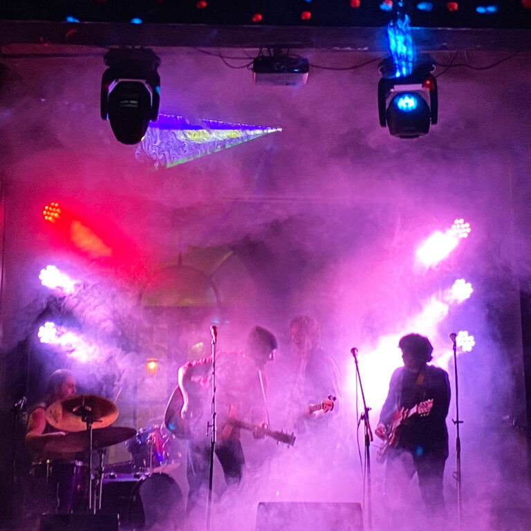 Musicians performing on a colourful, smoke-filled stage