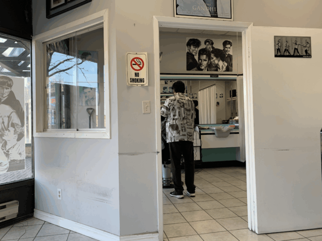 A man cuts hair in a small barbershop.