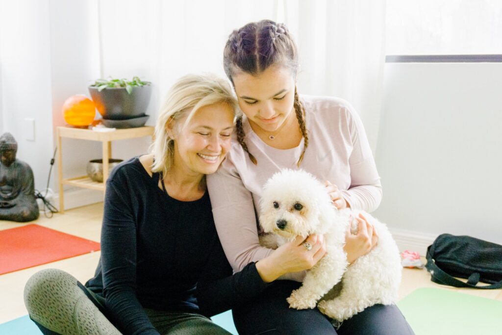 mom and daughter smiling with white puppy.