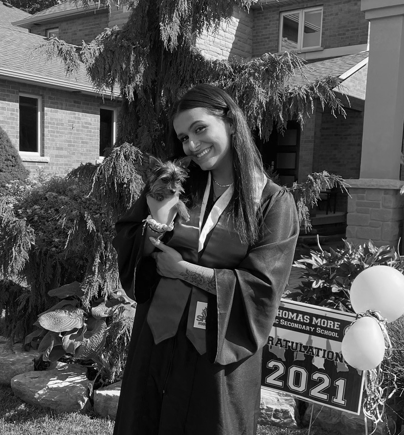 Aeva Alexandrovich in a graduation gown holding a dog.