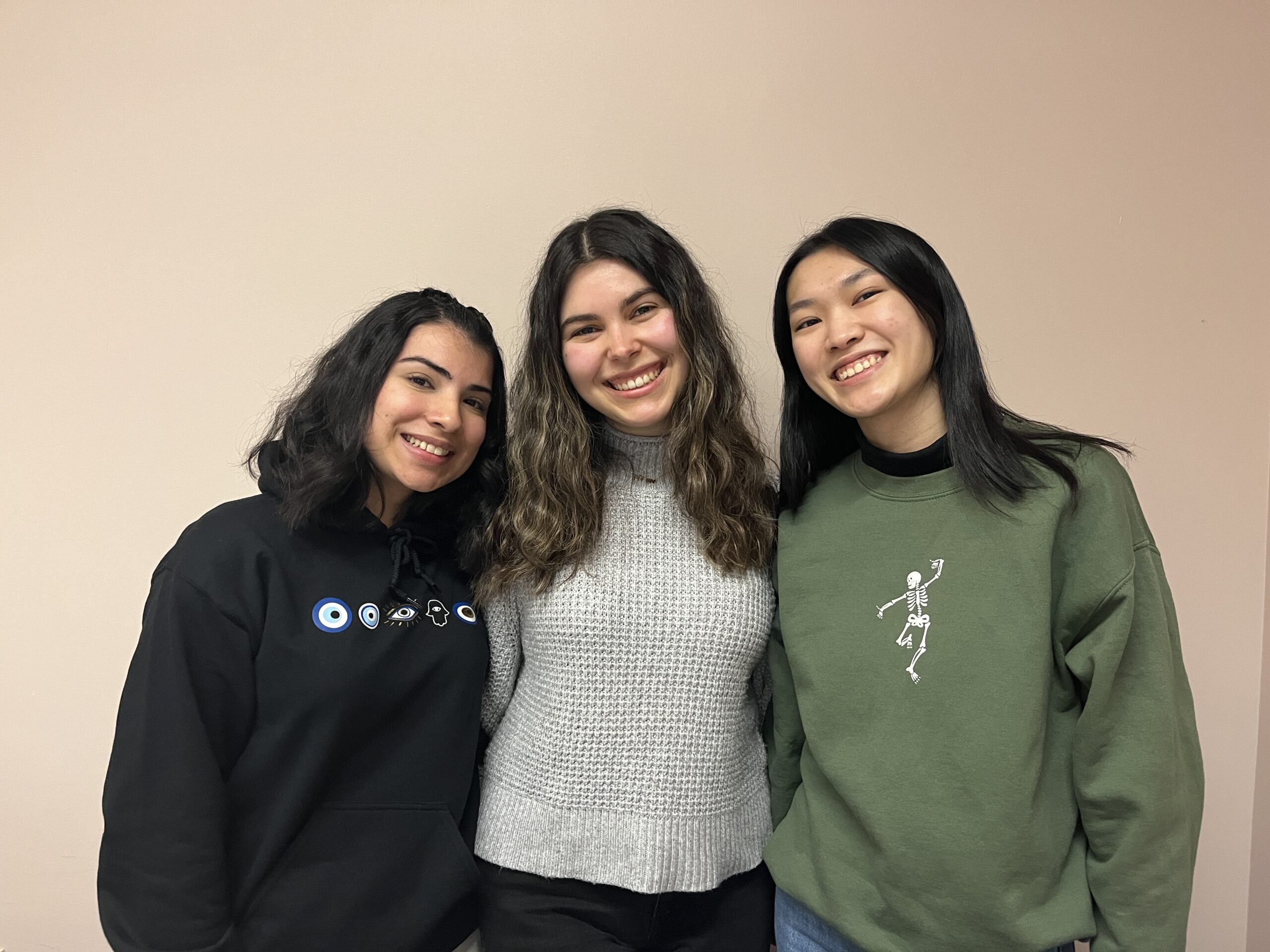 Three young women stand together.