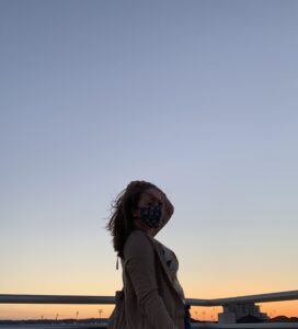 Girl wearing a mask and looking at camera in front of a sunset