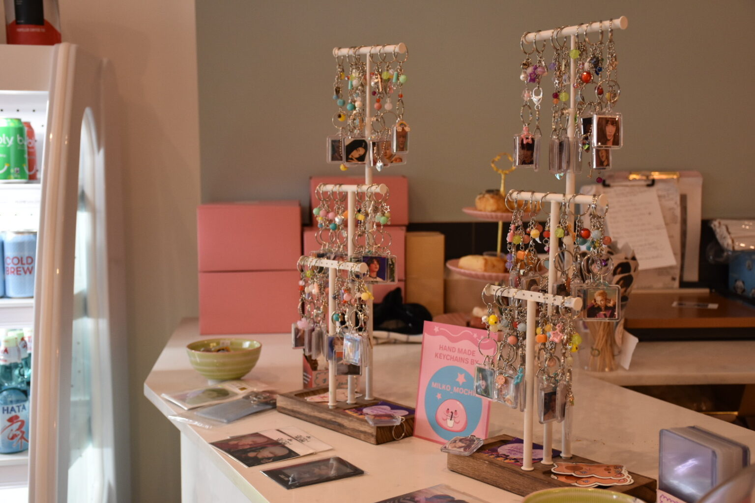 Keychains decorated with beads and photographs of K-pop idols are displayed for sale on the counter of a cafe
