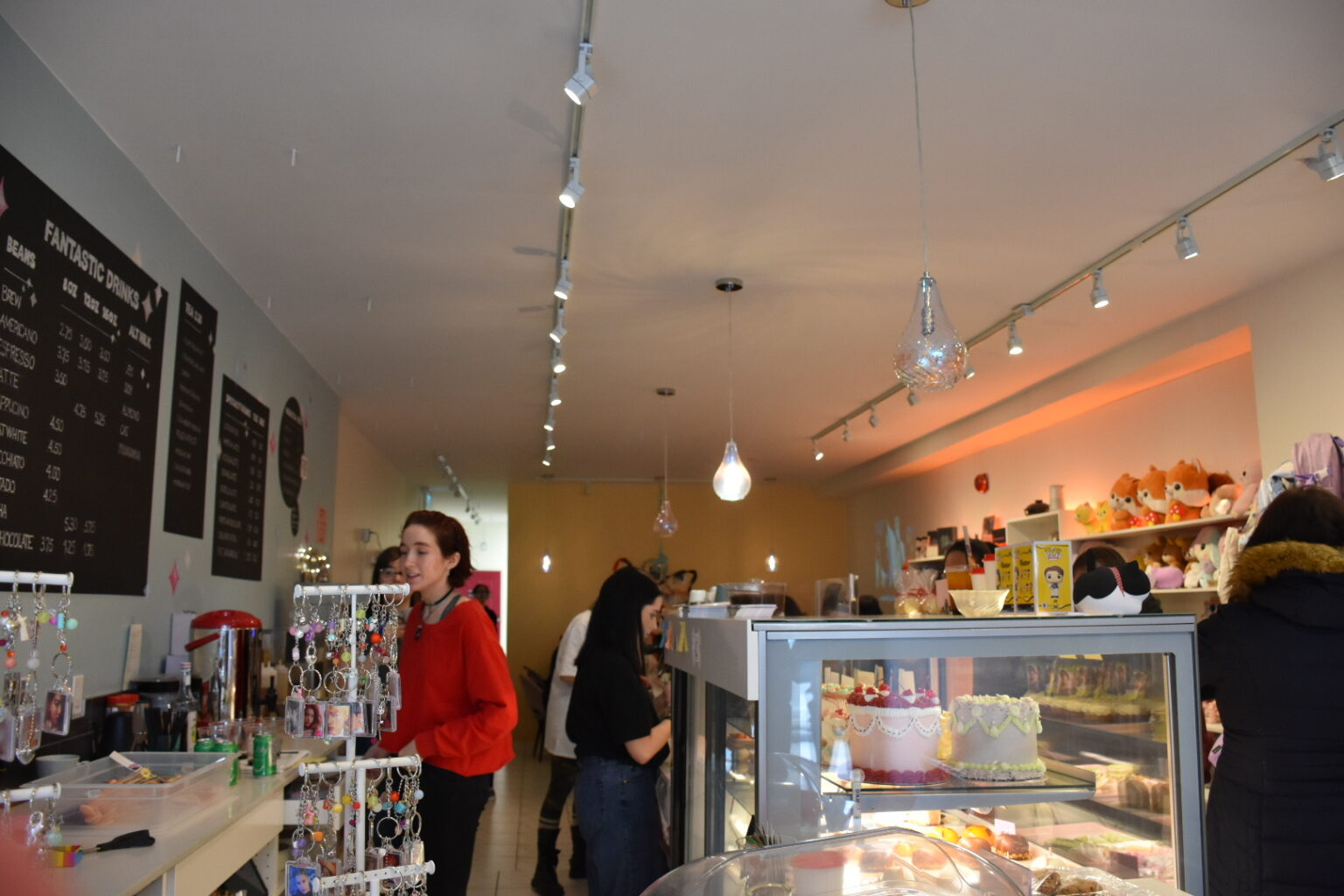 The light blue interior of a local cafe is filled with individuals awaiting drinks while baristas work behind the counter to deliver orders on time