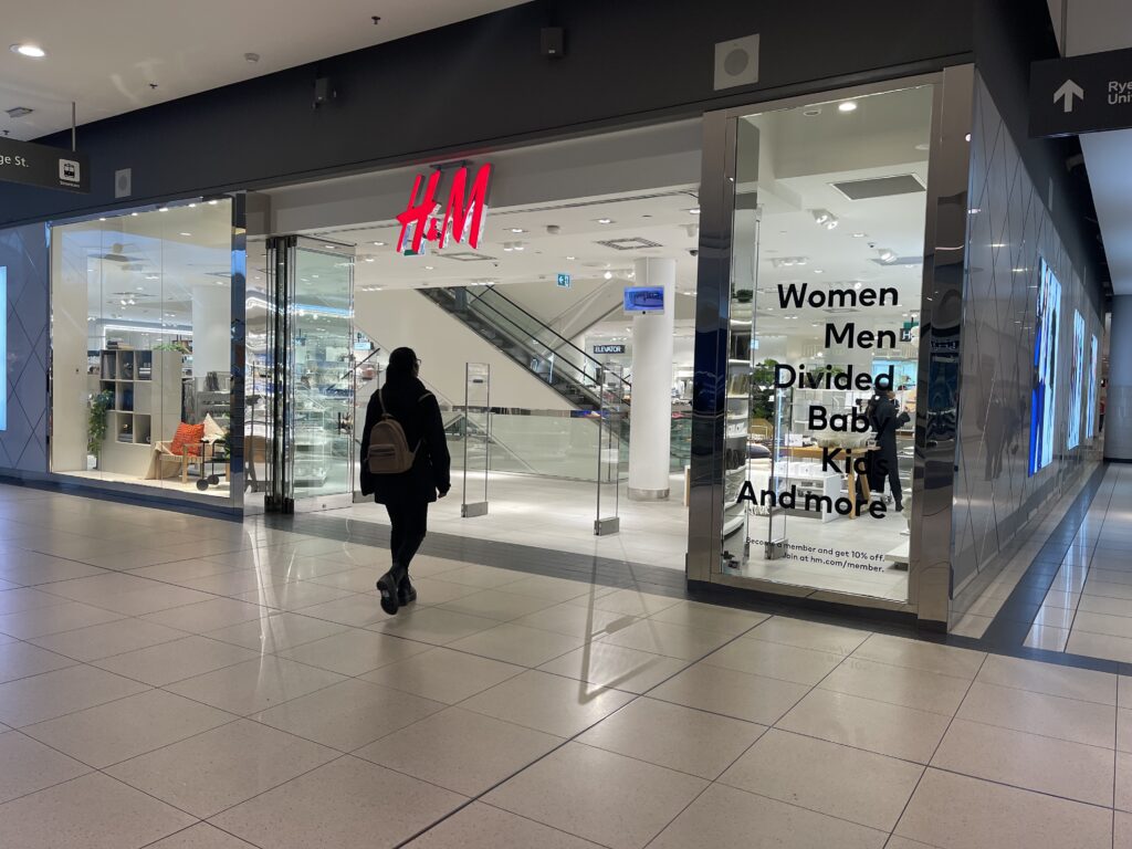 A shopper at the entrance of H&M and walking into the store at the Eaton Centre.