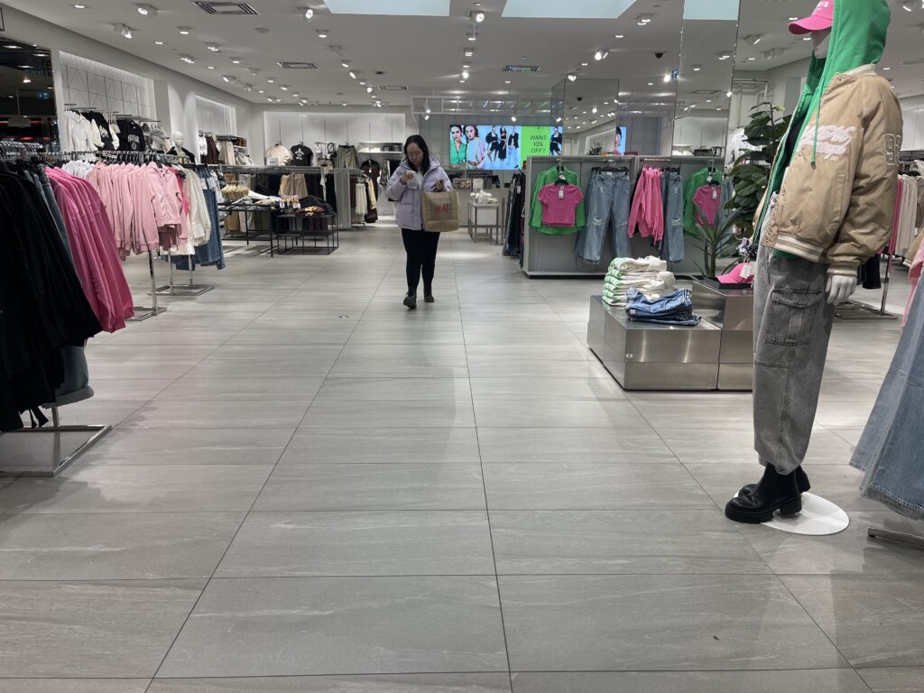 A shopper at the H&M store in Toronto looking at her shopping receipt while holding a bag of items purchased.