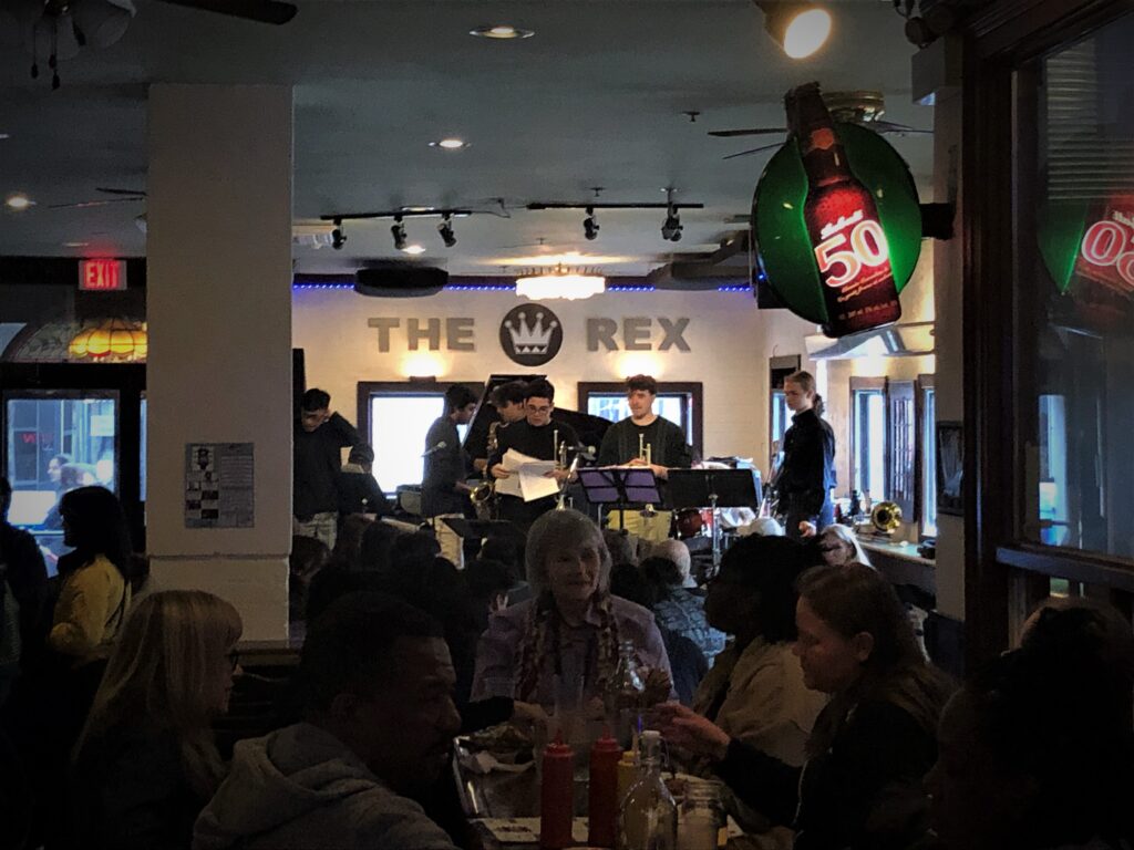 The William Carn 10tet band sets up the stage ahead of a performance at The Rex. People sit in the restaurant and eat as they wait.