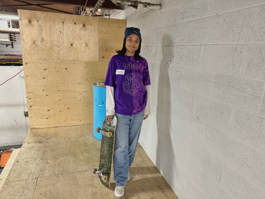 Woman standing on a skate ramp holding a skateboard