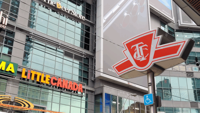 A TTC Sign hangs in front of Yonge-Dundas Square