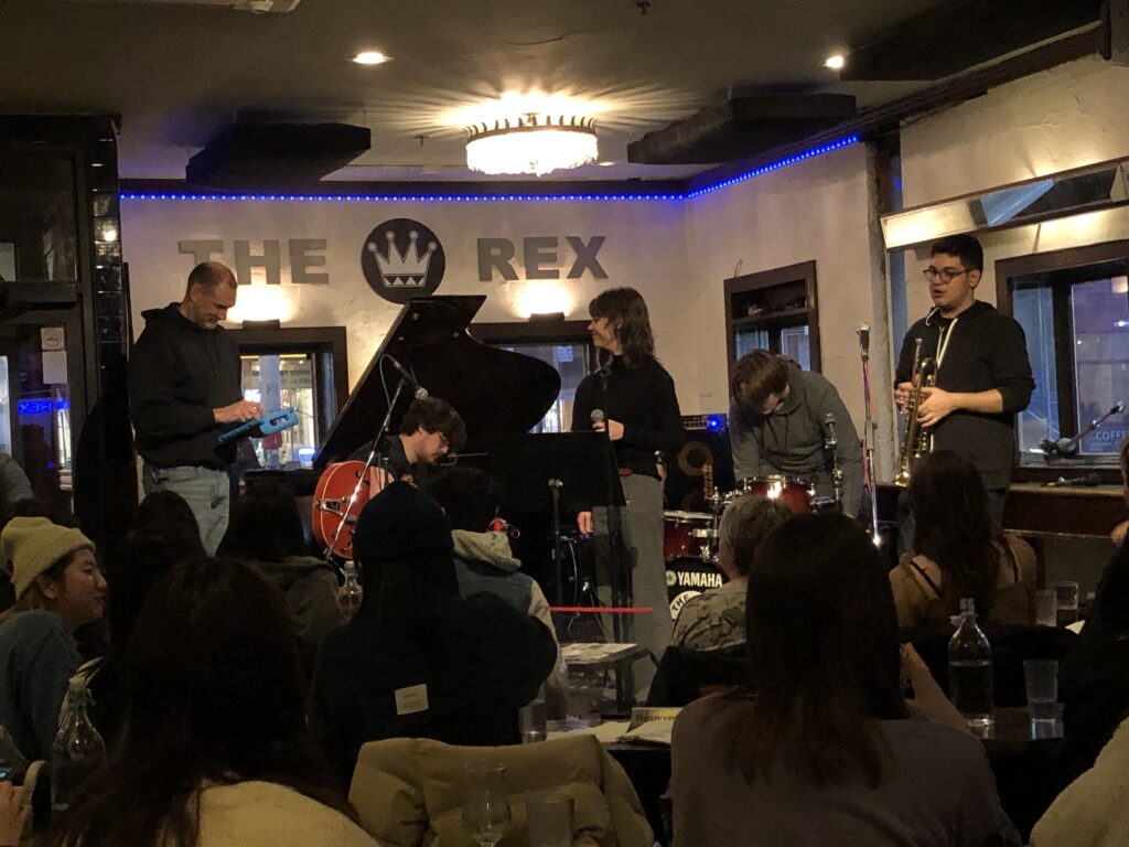 Tom Tytel sets up a microphone as a student ensemble gets set to play in front of a packed crowd at The Rex Hotel Jazz and Blues Bar