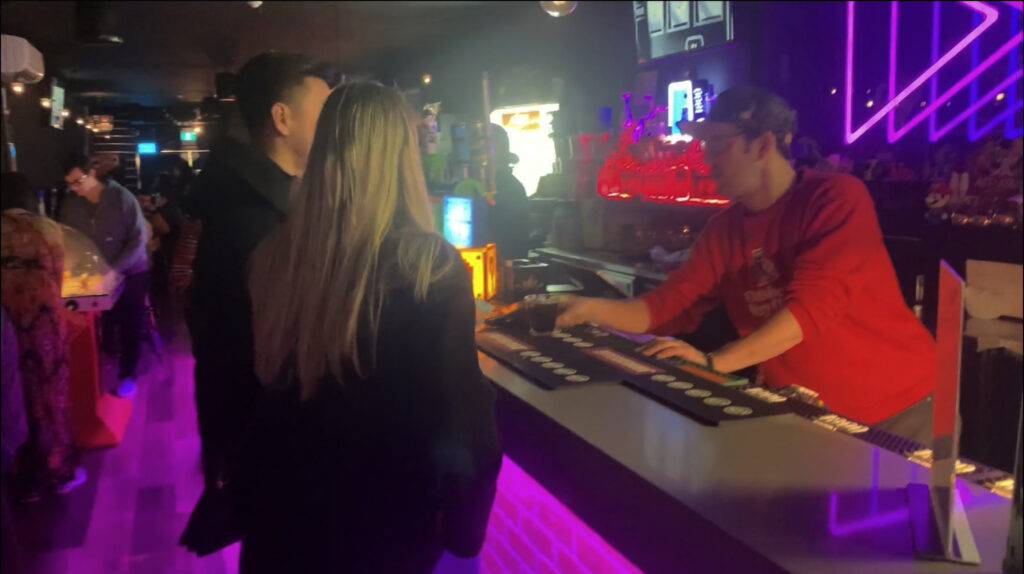 Bartender handing a drink over to two guests at the bar.