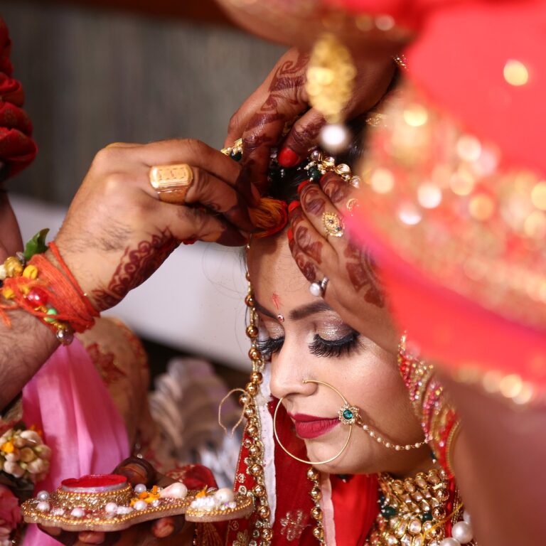 An Indian wedding featuring a husband and wife wearing red traditional Indian clothes.