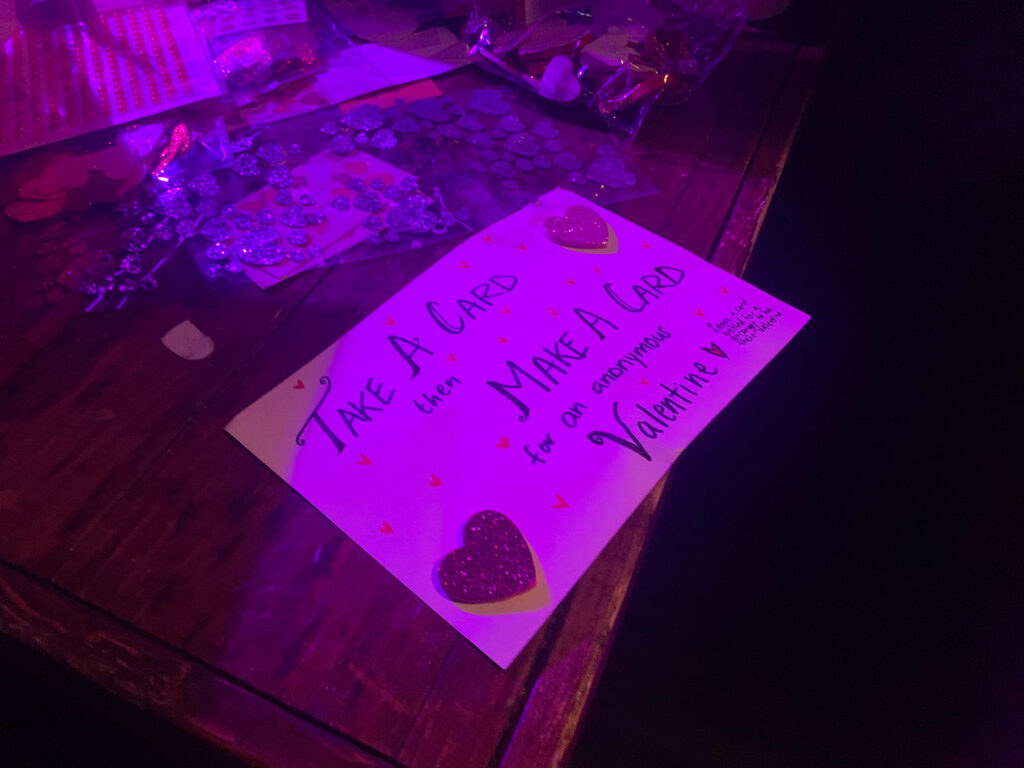 Sign stating “Take a card then make a card for an anonymous Valentine.”