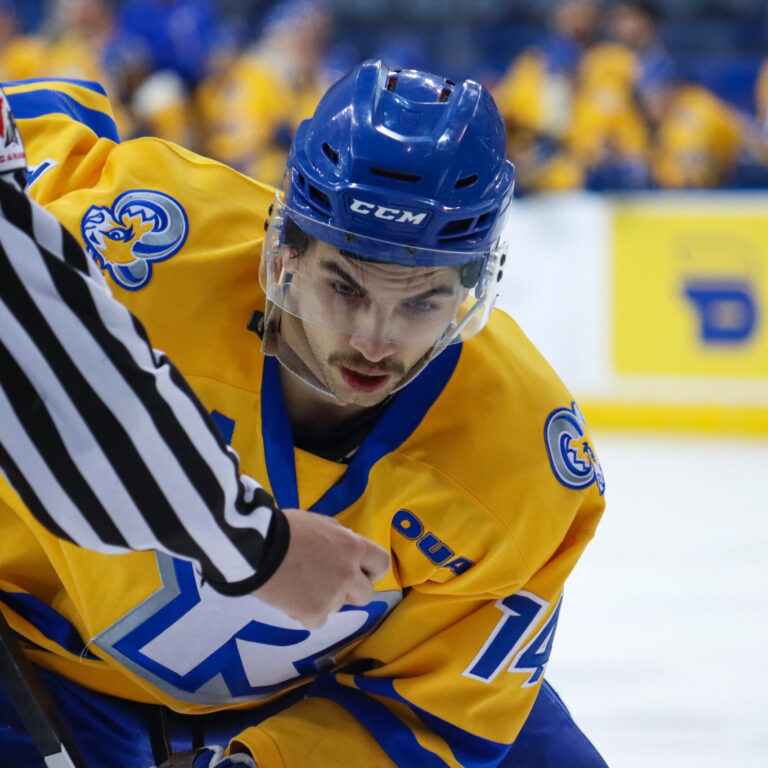 Hockey player getting ready to get the puck before the referee drops it