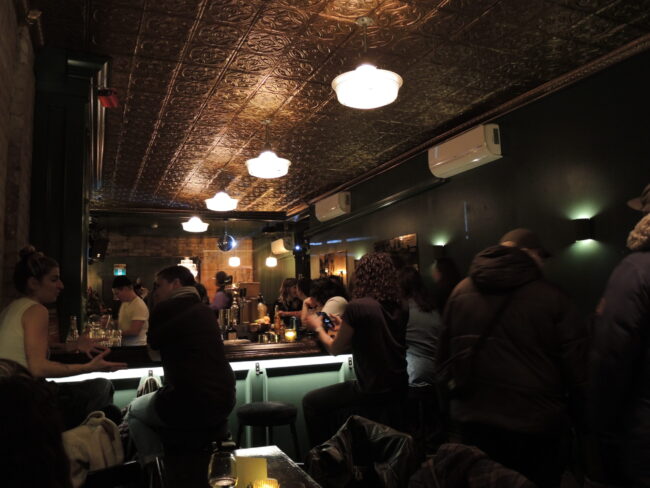 Patrons gather around a dimly lit bar