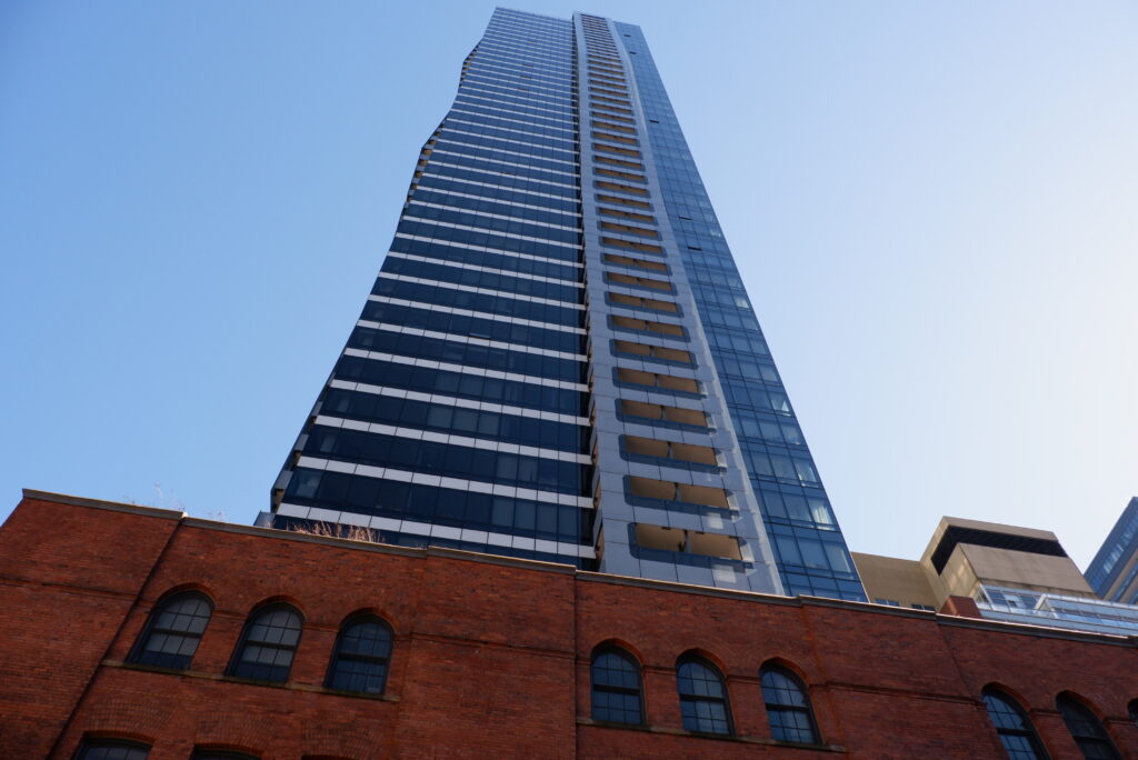 An old red brick building with a tall condo tower protruding from the top