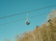 Photograph of ski lift chair with a blue sky and trees in the background.
