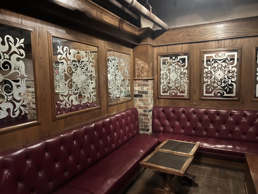 The waiting lounge area of O'Noir. There are burgundy-coloured leather lounge benches and wooden/mirrored panelled walls.