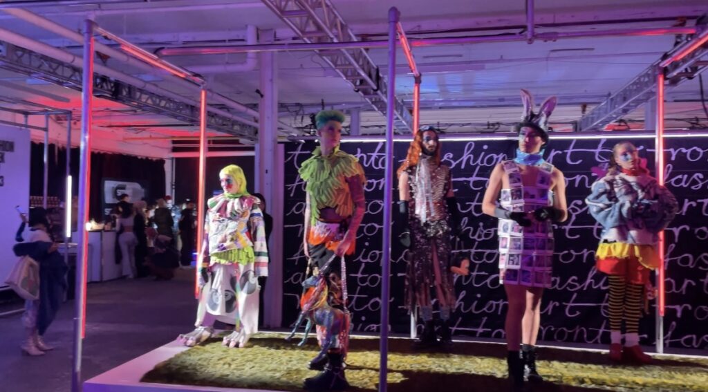 Five models at Fashion Art Toronto in futuristic and colourful outfits on a black and white backdrop