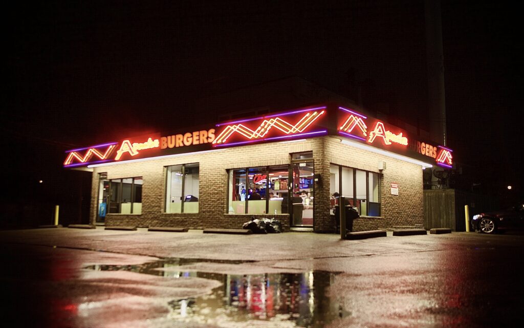 Apache Burgers restaurant lit up with LED signage on a rainy night