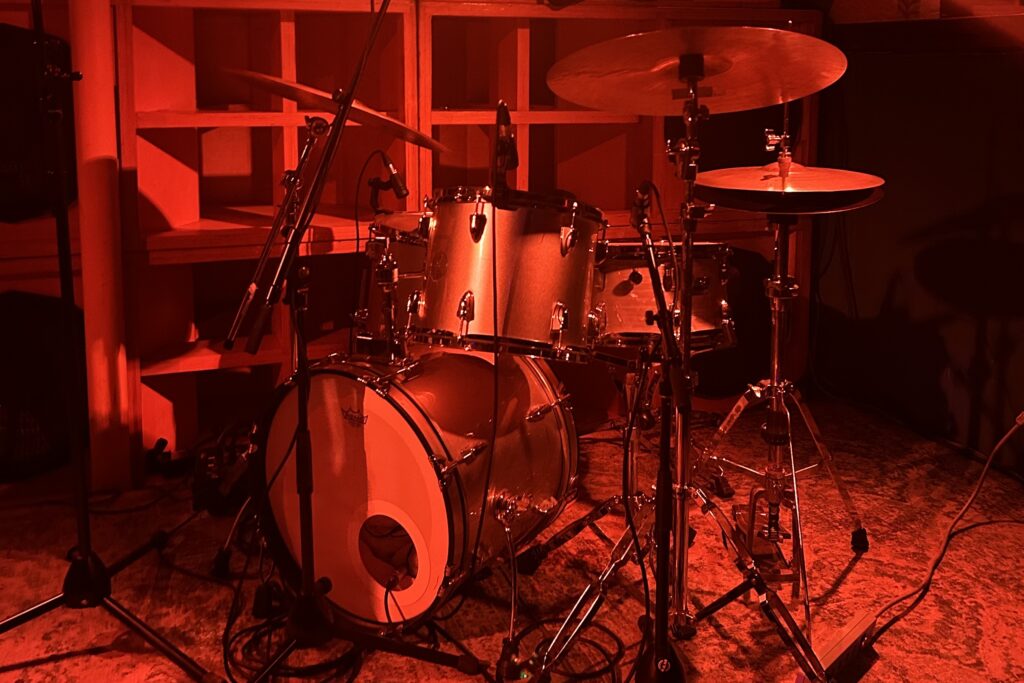 Image of a drum set on a stage with red LED lighting.
