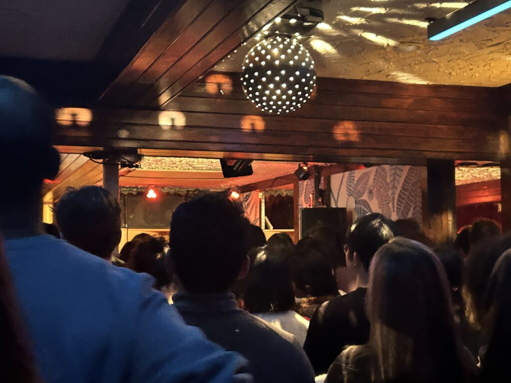 Image of an audience of people with a disco ball hung from the ceiling.