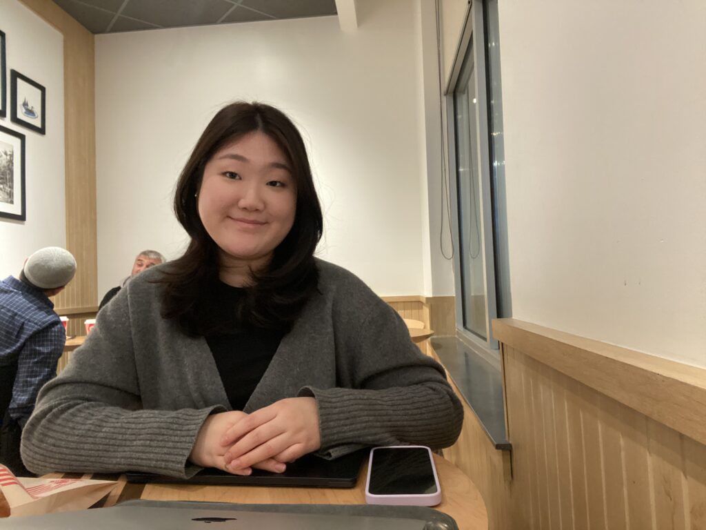 A smiling Korean woman sitting in a cafe.