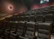 Many rows of empty movie theatre chairs.