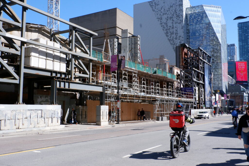 A person on a bicycle rides past a construction site in downtown Toronto