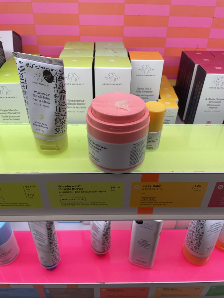 Some colourful skincare products on a neon green display with product stains.